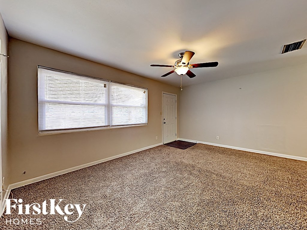 an empty bedroom with a ceiling fan and a window