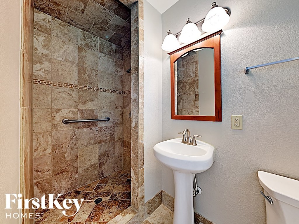 a bathroom with a shower sink and toilet and a mirror