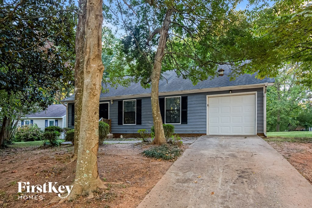 A house with a garage is surrounded by trees.