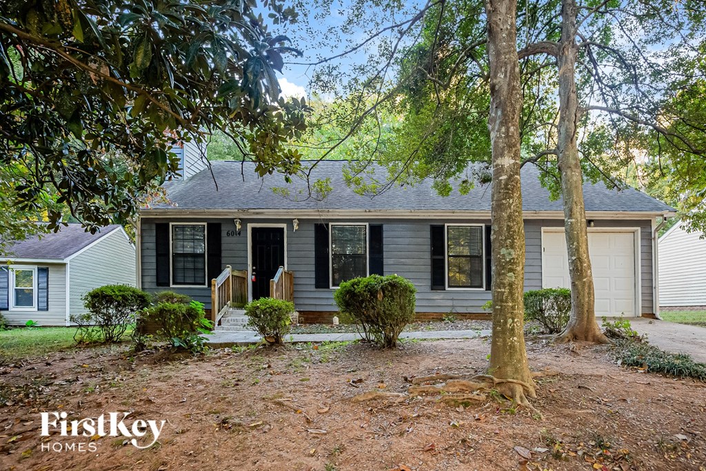 A house with a front yard and a tree in the foreground.