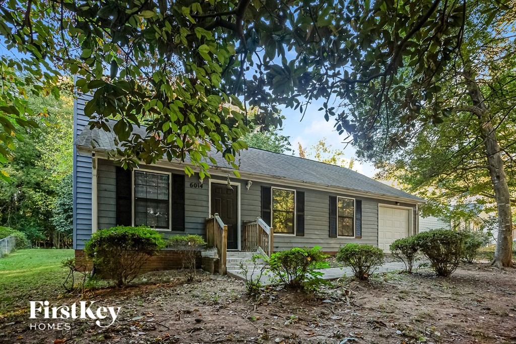 A house with a porch and a tree in front of it.