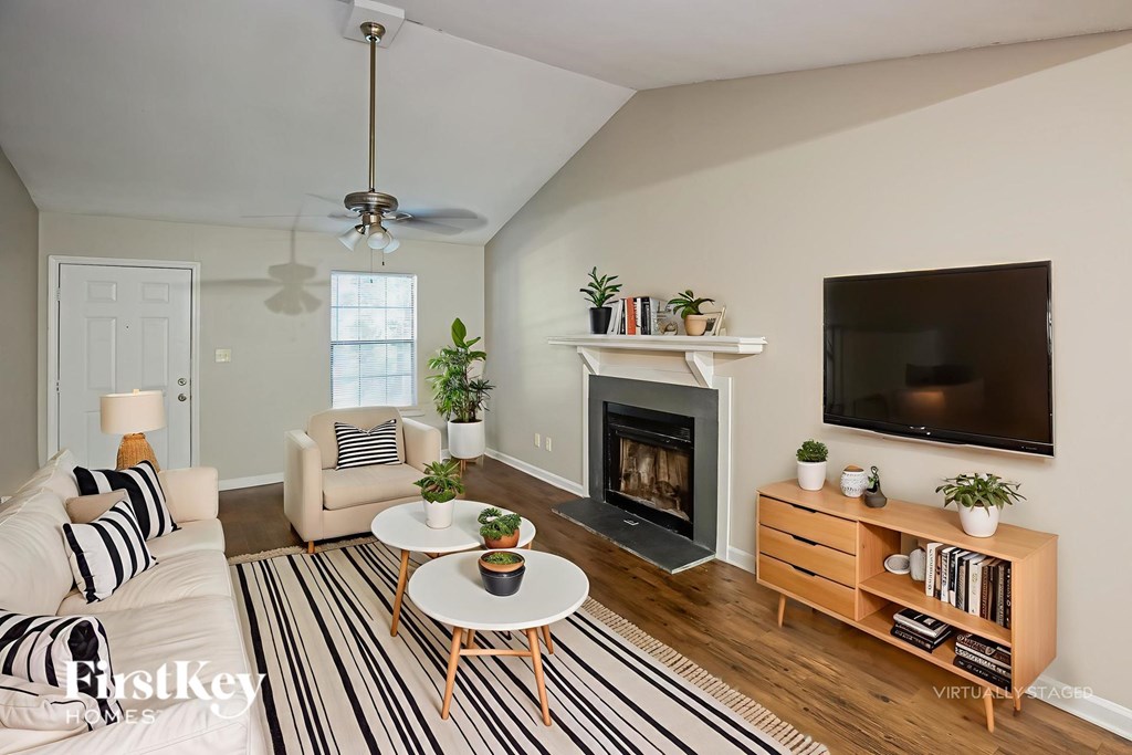 A living room with a fireplace and a television on the wall.