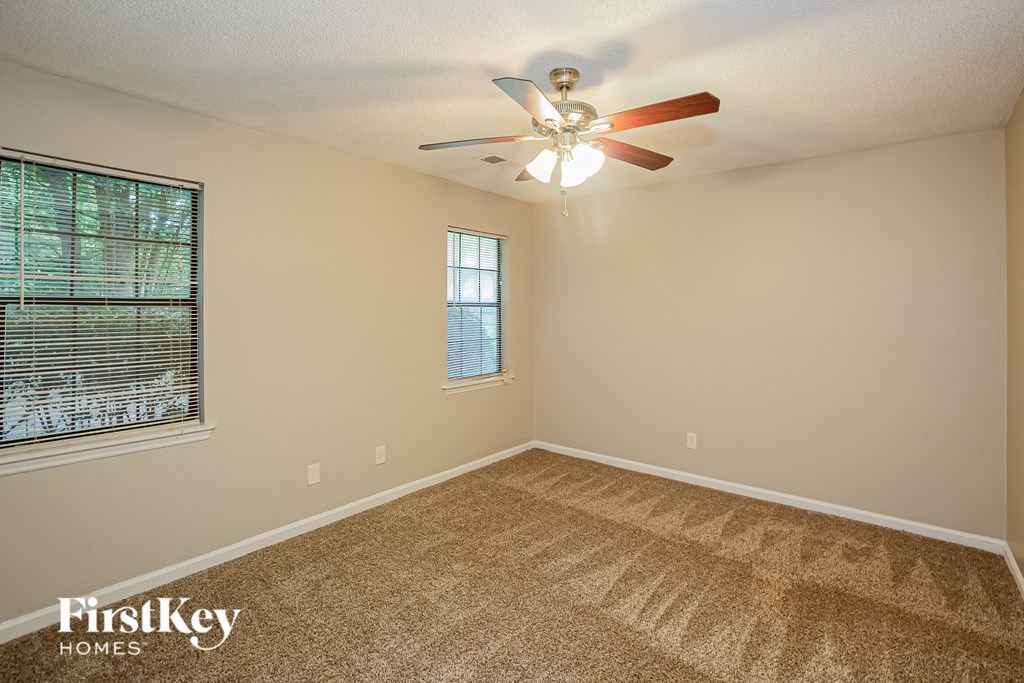 A room with a ceiling fan and a window with blinds.