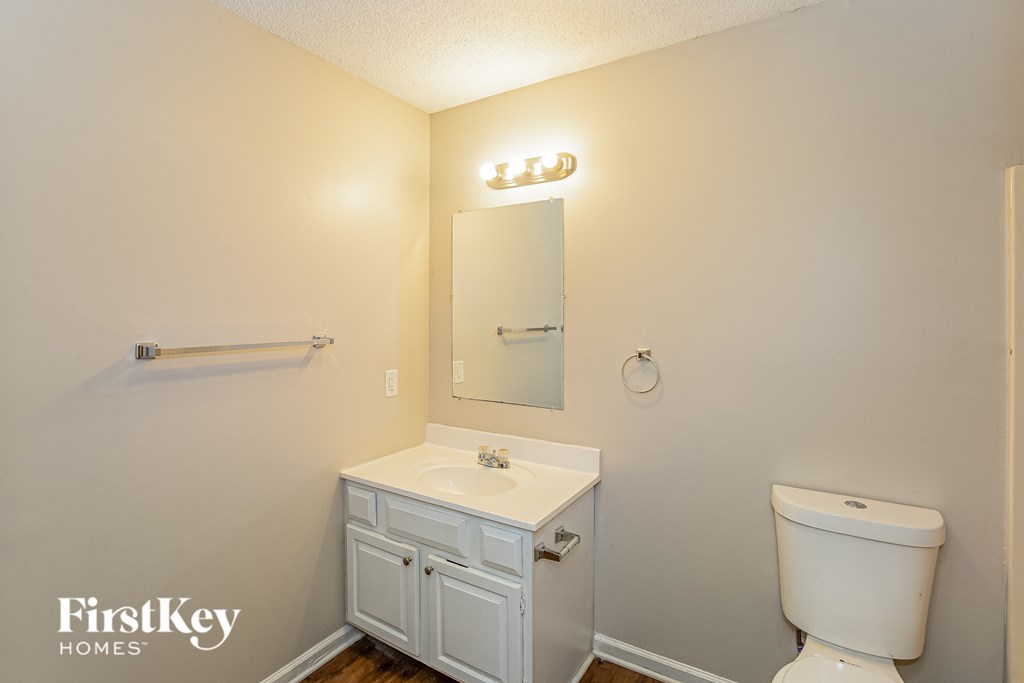 A white bathroom with a toilet, sink and medicine cabinet.