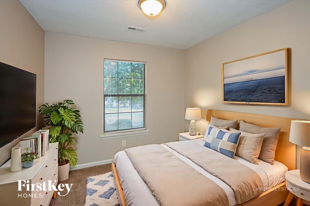 A bedroom with a large bed, a window, and a painting on the wall.