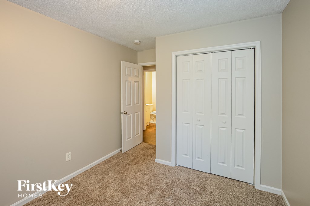 A carpeted room with a white door and a white wall.