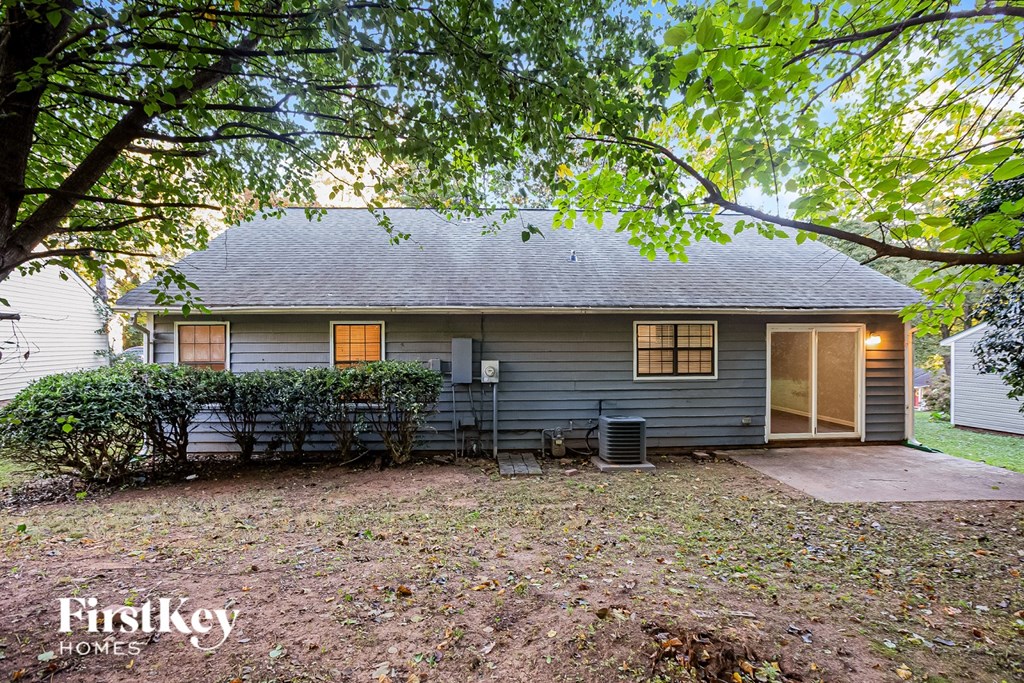 A house with a grey roof and a tree in front of it.