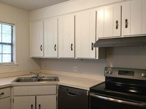 a kitchen with white cabinets and a stove and a sink