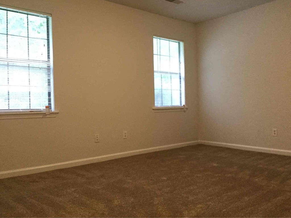 an empty room with two windows and a carpeted floor