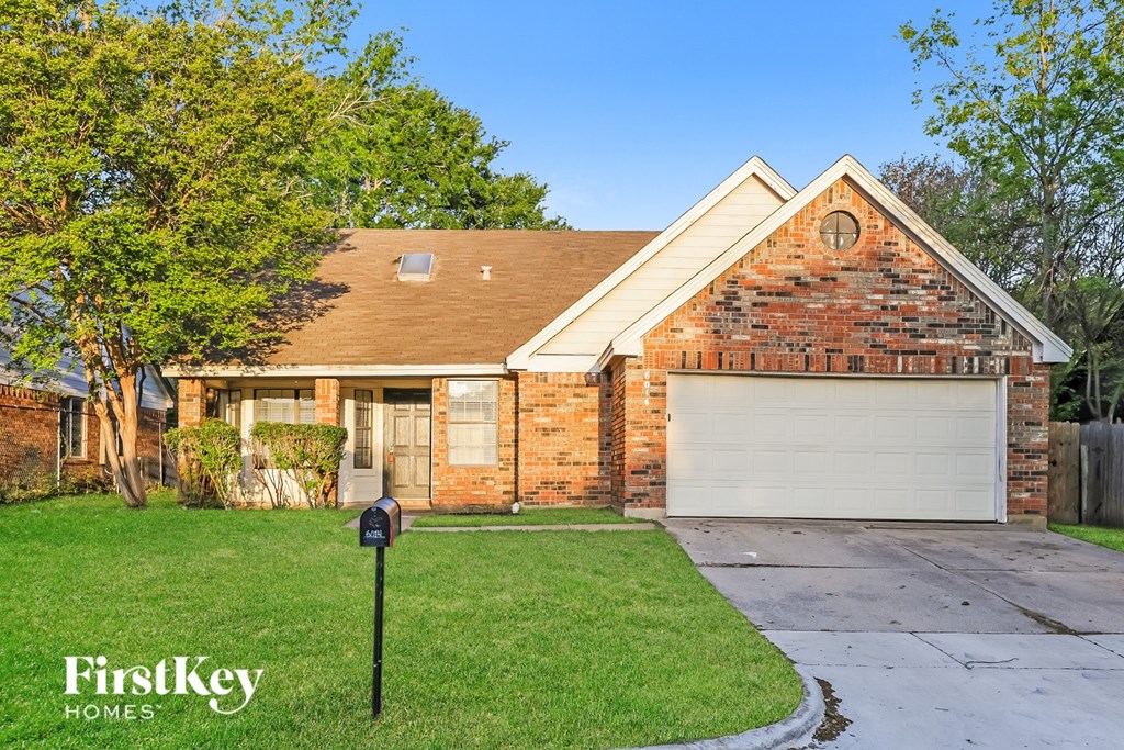 A brick house with a white garage door and a mailbox in front.
