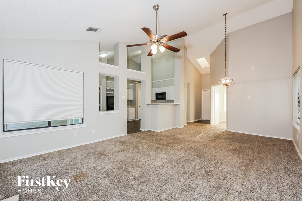 A spacious room with a ceiling fan and a carpeted floor.