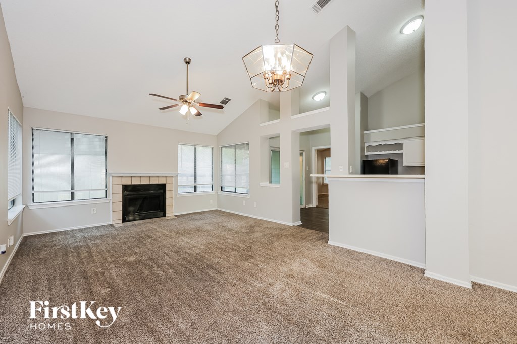 A spacious living room with a fireplace and a chandelier.