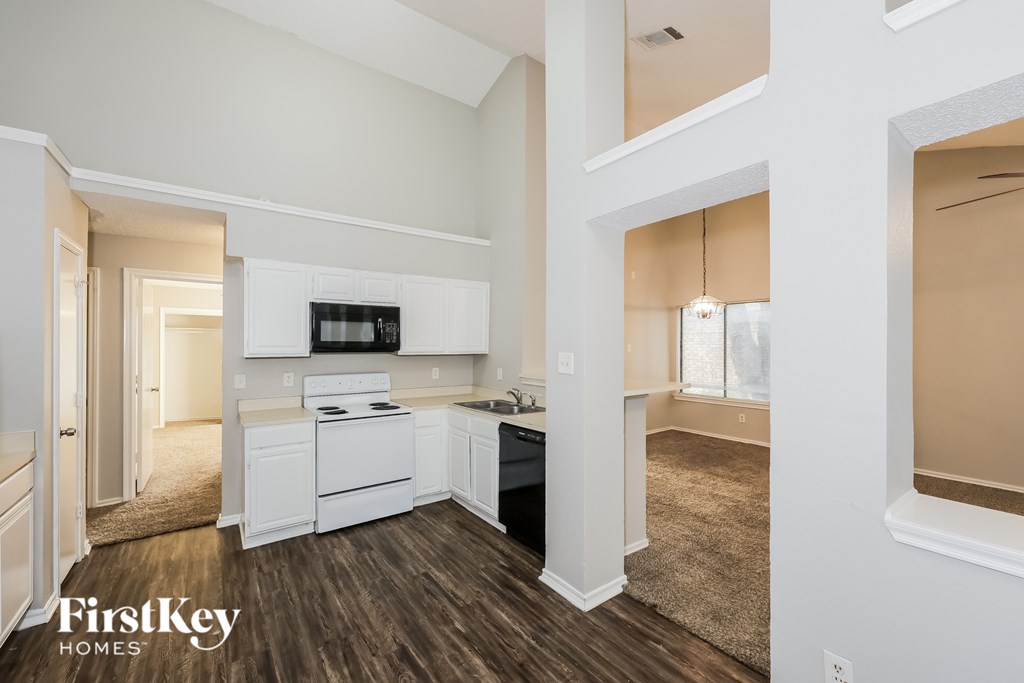 A kitchen with white appliances and wooden floors.