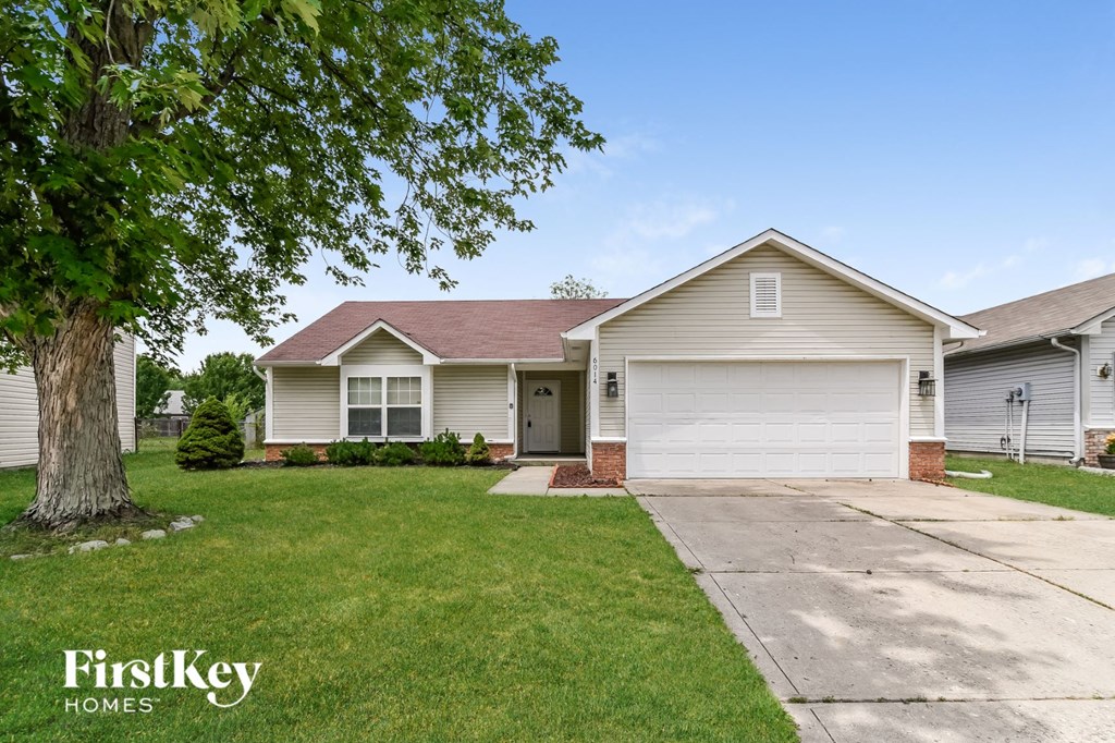 a white house with a driveway and a tree