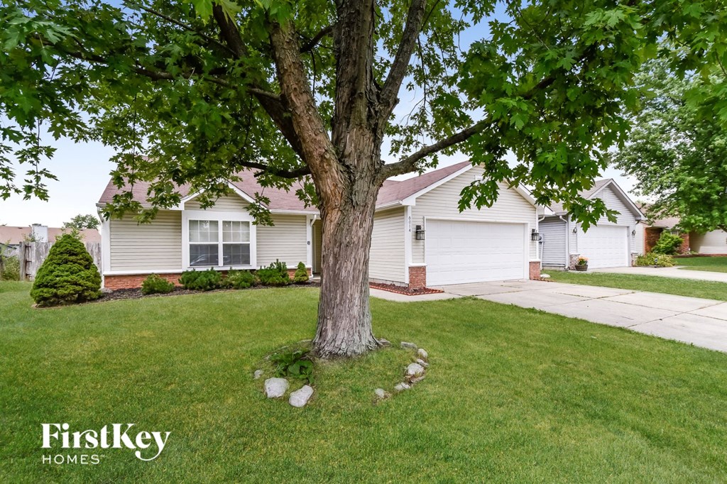 a white house with a large tree in the front yard