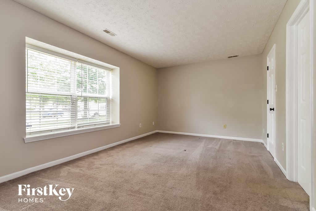 an empty living room with a large window and carpet