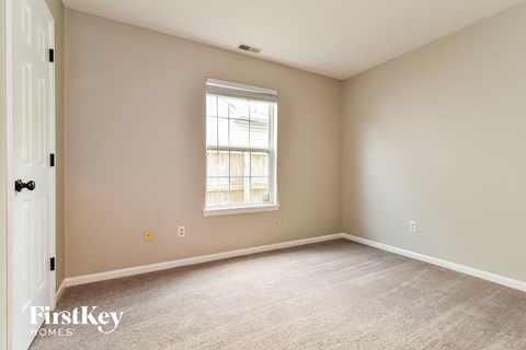 a spacious living room with carpet and a window