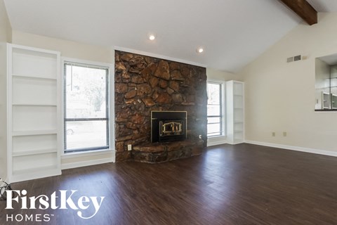 a living room with a stone fireplace and wooden floors