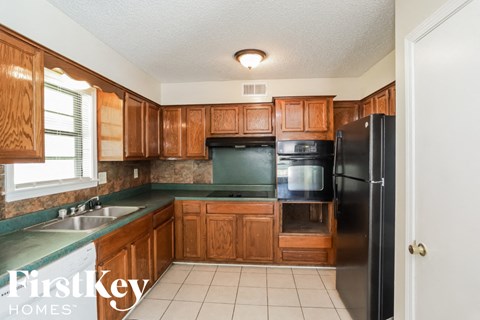 a kitchen with wooden cabinets and a black refrigerator and a sink