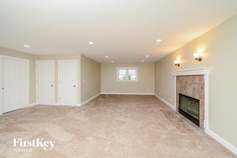 A spacious living room with a fireplace and beige carpeting.