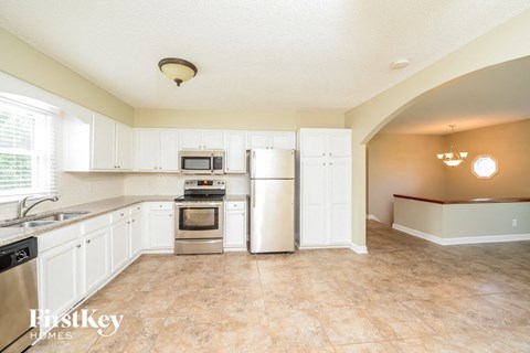 A kitchen with white cabinets and a tiled floor.