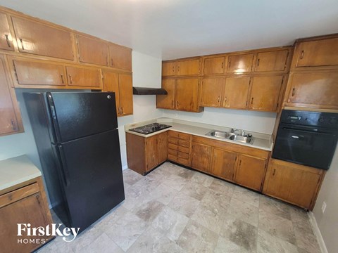 a kitchen with wooden cabinets and a black refrigerator
