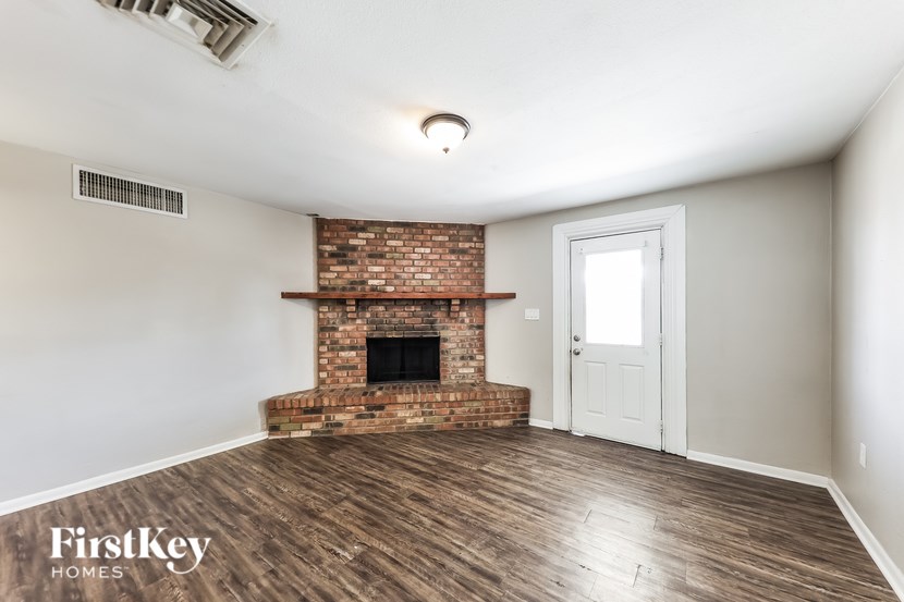 A room with a brick fireplace and wooden floors.