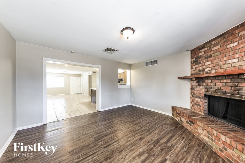 A room with a brick fireplace and wooden floors.