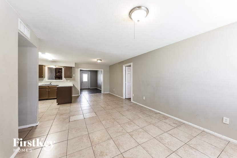 A spacious empty room with tiled flooring and white walls.