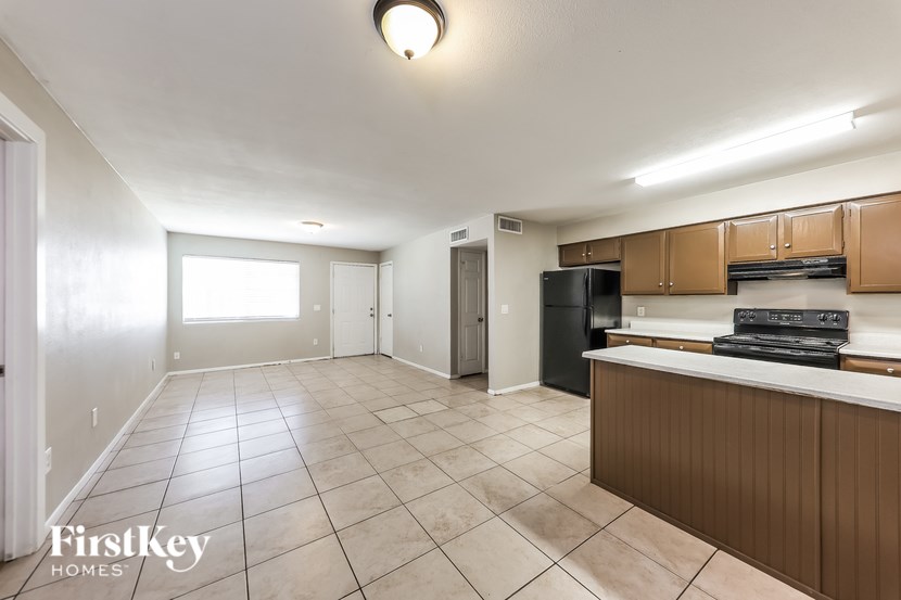 A kitchen area with a black fridge and brown cabinets.