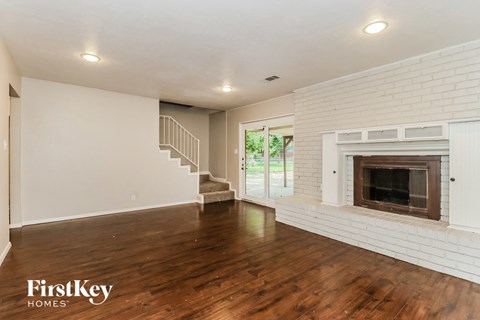 a living room with a fireplace and wooden floors and a staircase