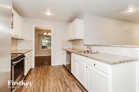 a kitchen with white cabinets and marble counter tops