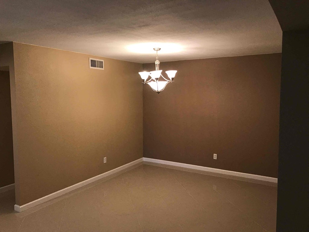 a empty living room with brown walls and a chandelier