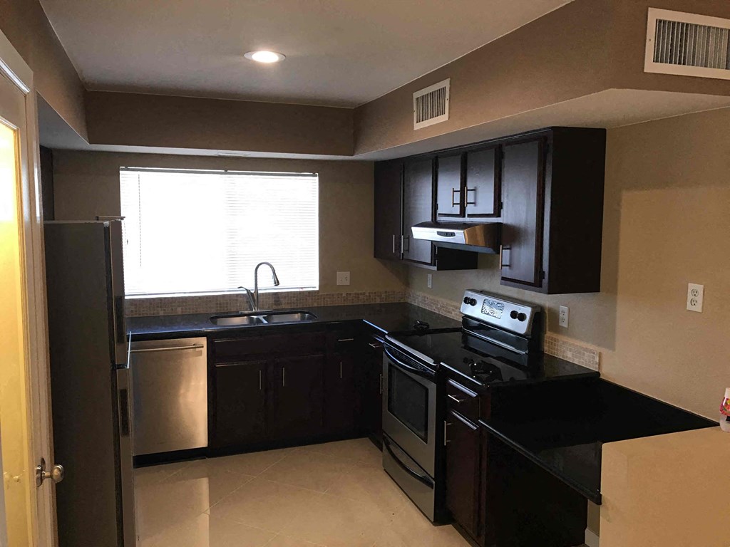 a kitchen with black counter tops and black appliances