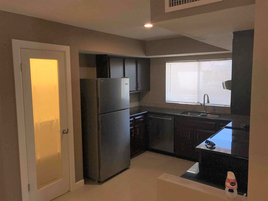 a kitchen with black cabinets and a stainless steel refrigerator