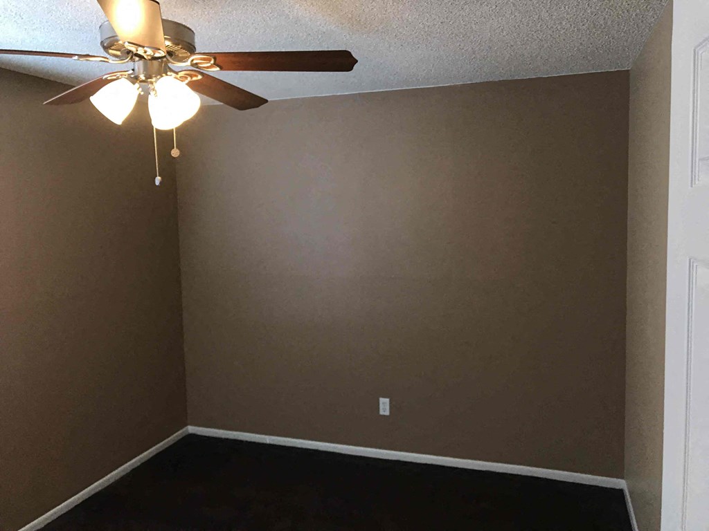 a empty room with a ceiling fan and a white door
