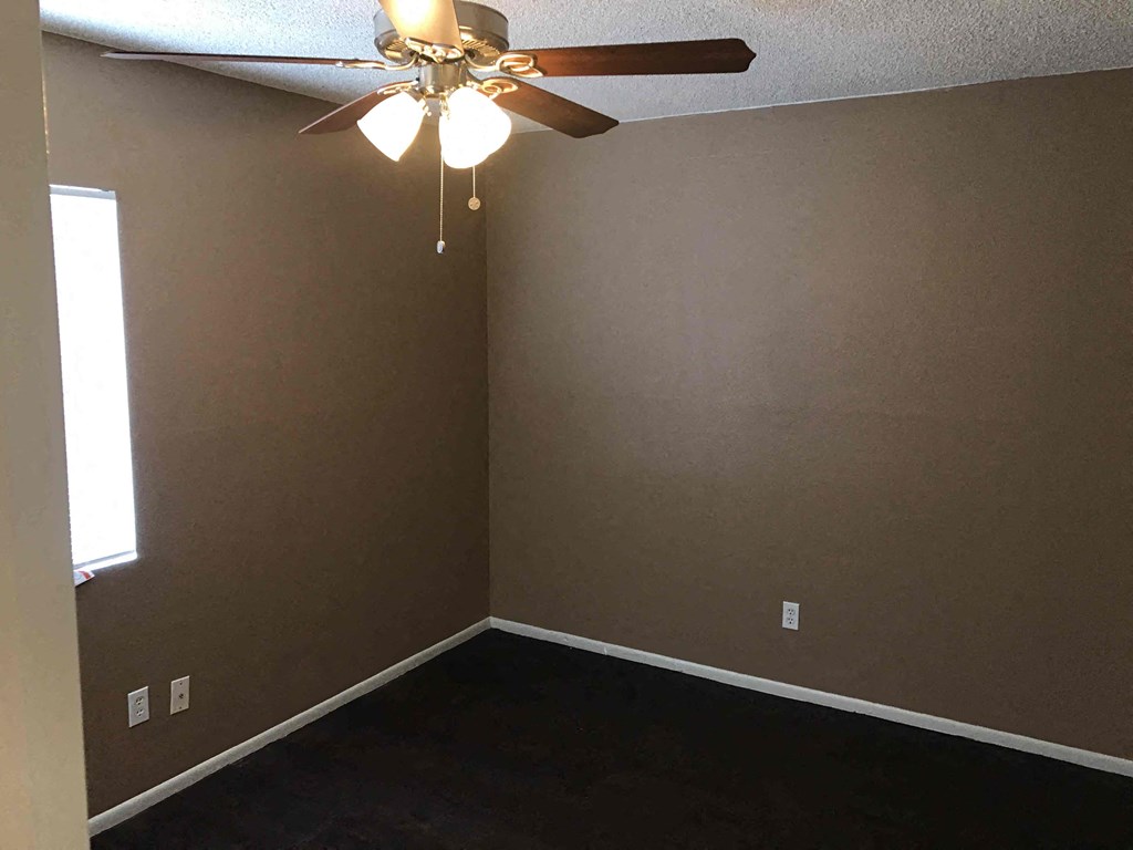 a empty room with a ceiling fan and a window