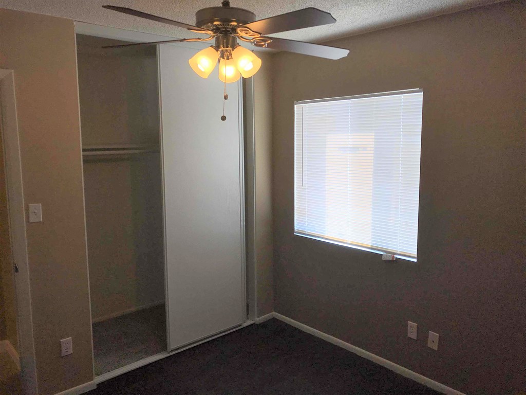 a bedroom with a ceiling fan and a window