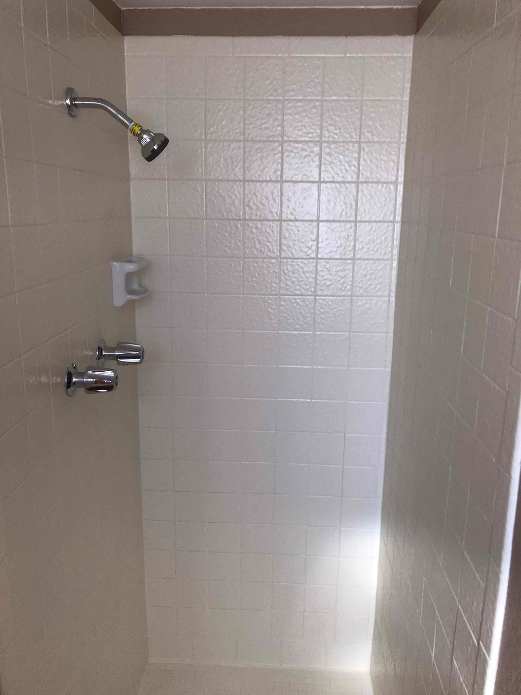 a white tiled shower in a bathroom with a shower head