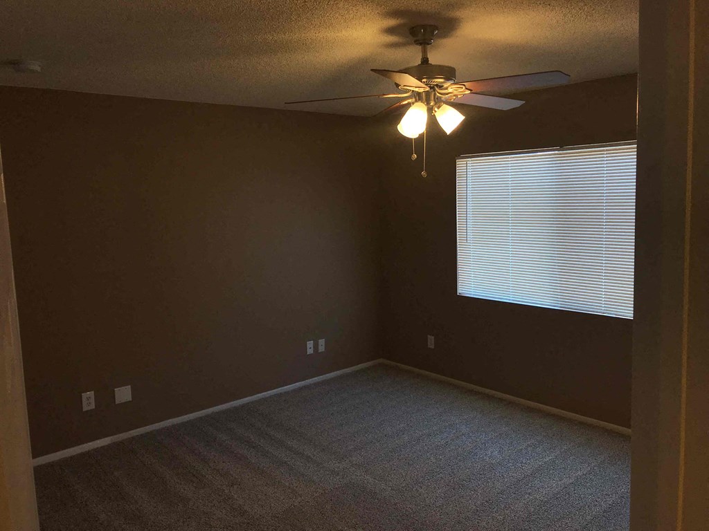 an empty bedroom with a ceiling fan and a window