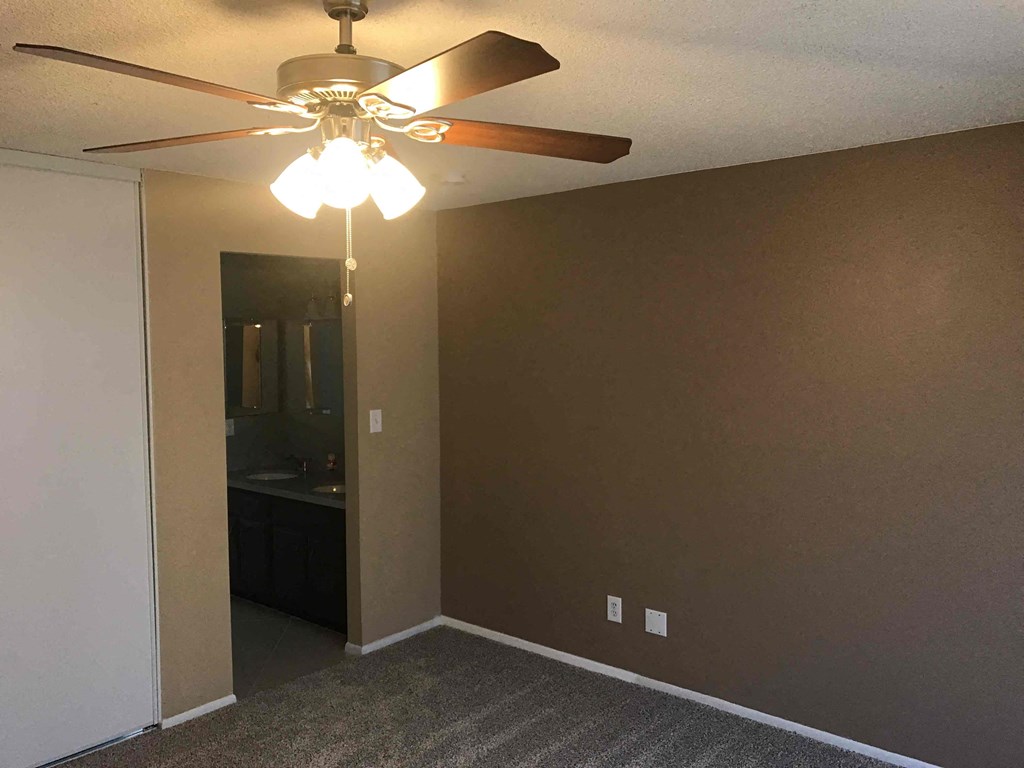 a empty living room with a ceiling fan and a closet