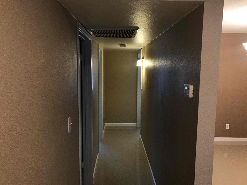 a hallway with a door to a room and a dark wall