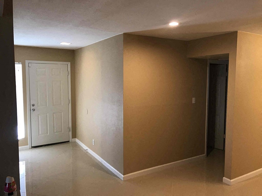 an empty living room with a white door and brown walls