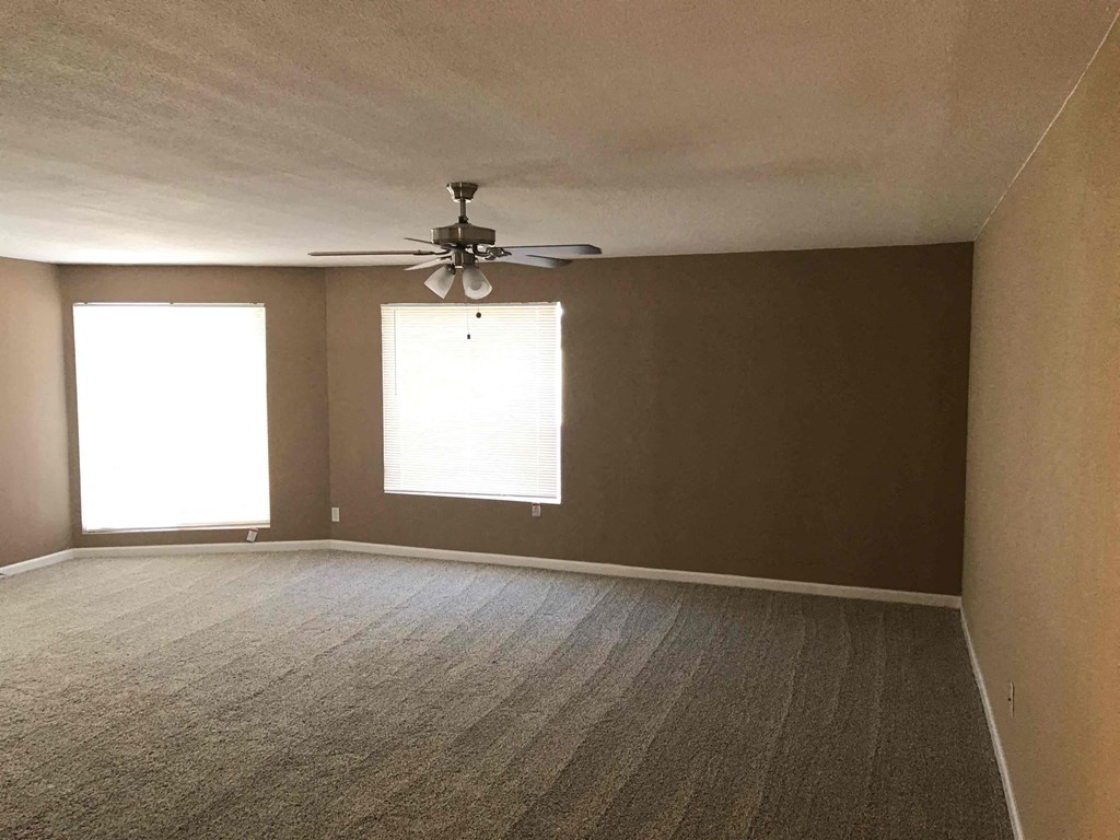 an empty living room with a ceiling fan and a window