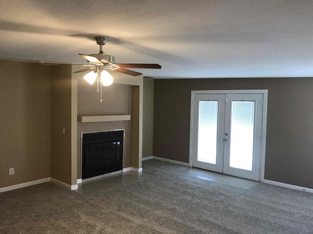 a living room with a fireplace and a ceiling fan