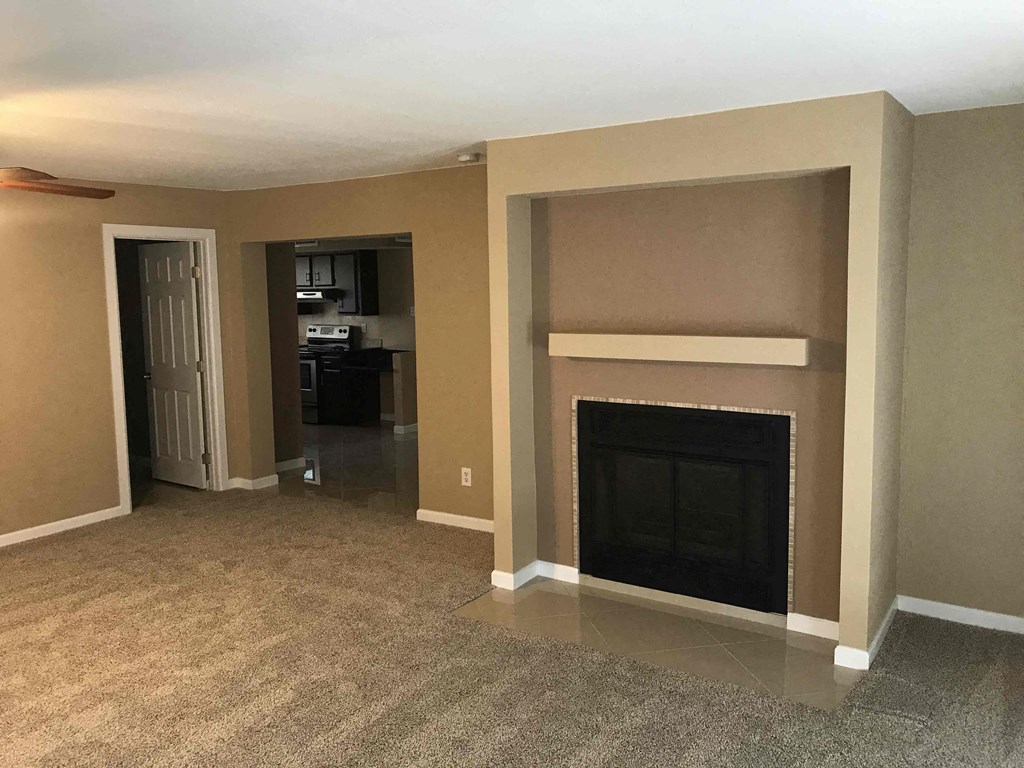 a living room with a fireplace and a door to a kitchen