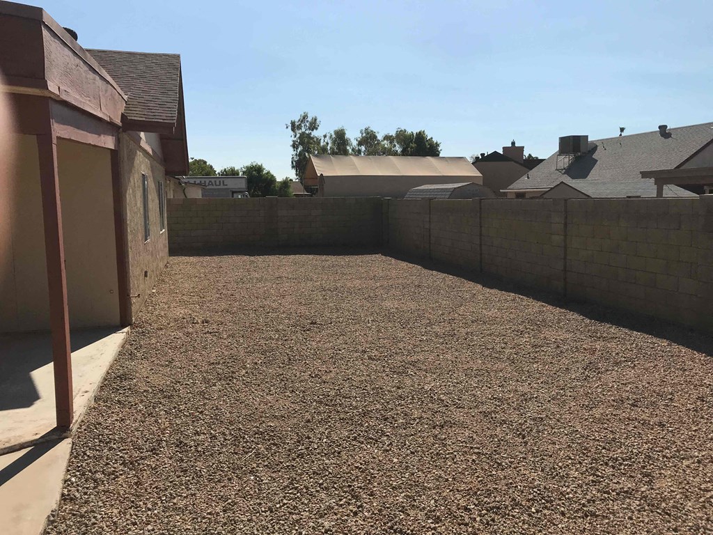 a backyard with gravel and a fence and a house