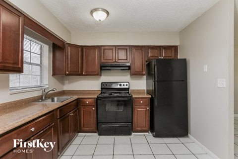 A kitchen with brown cabinets and black appliances.