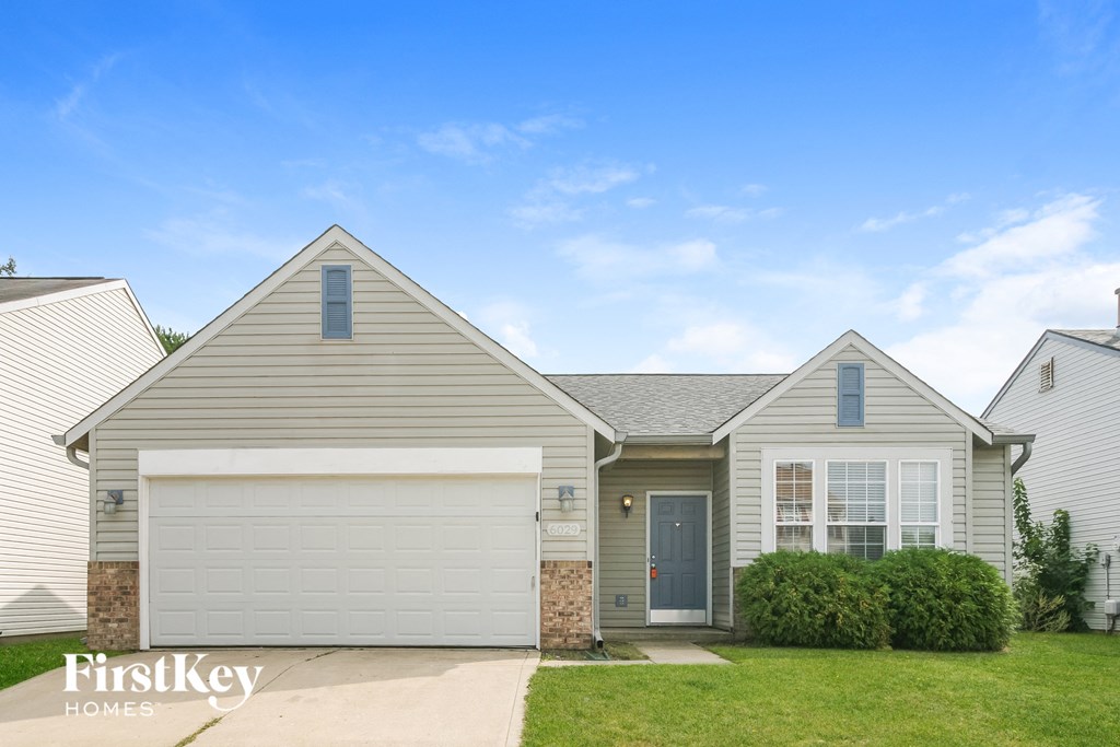 a white house with a white garage door and a green lawn