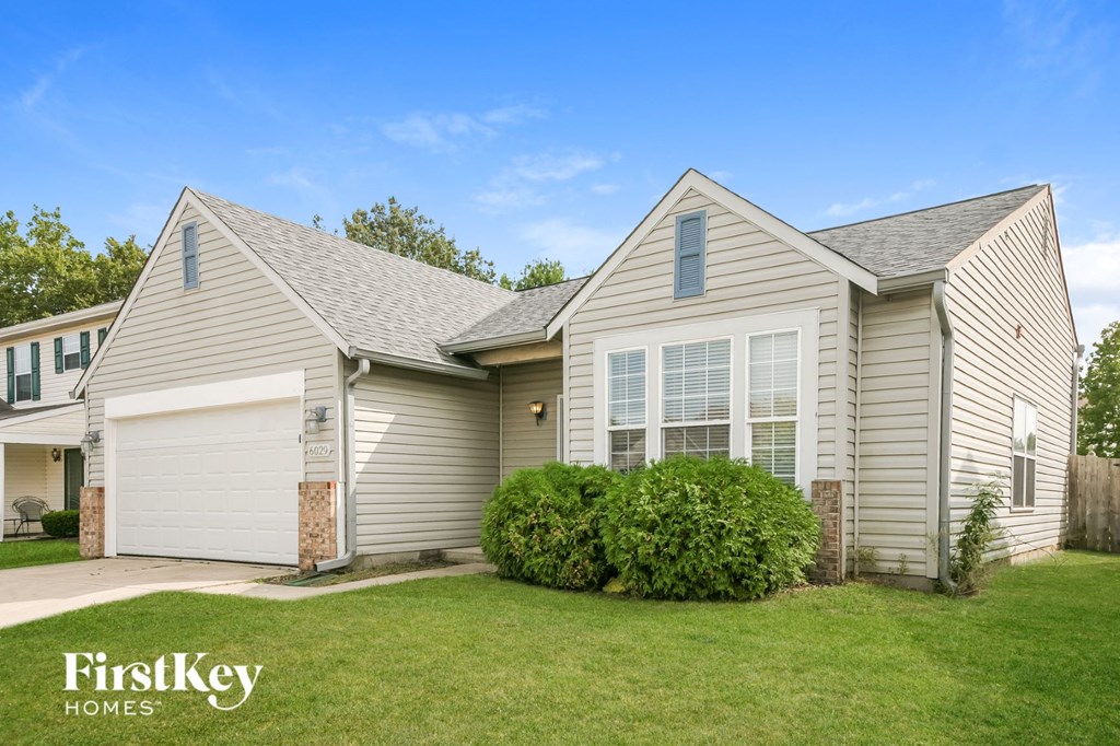 a white and gray house with a lawn in front of it
